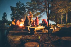 people sitting around a campfire in the woods